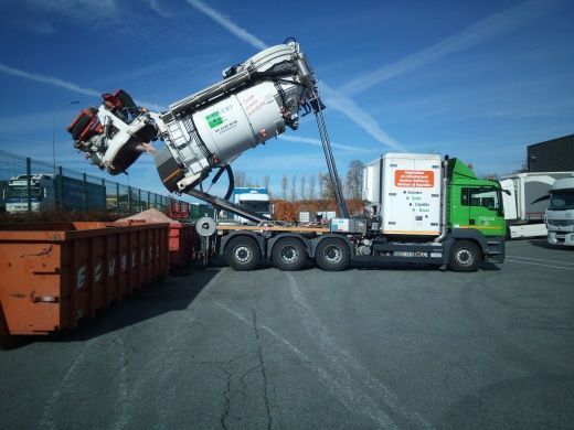 Un semi-remorque blanc et vert avec une remorque verte est garé à l'extérieur.