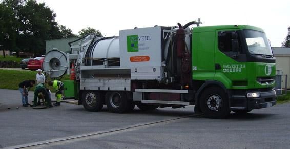 Camion aspirateur vert avec des employés sur place, en train de nettoyer.