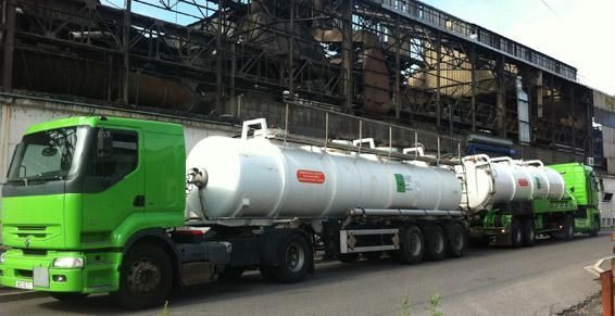 Des camions-citernes verts sont stationnés devant un bâtiment industriel.