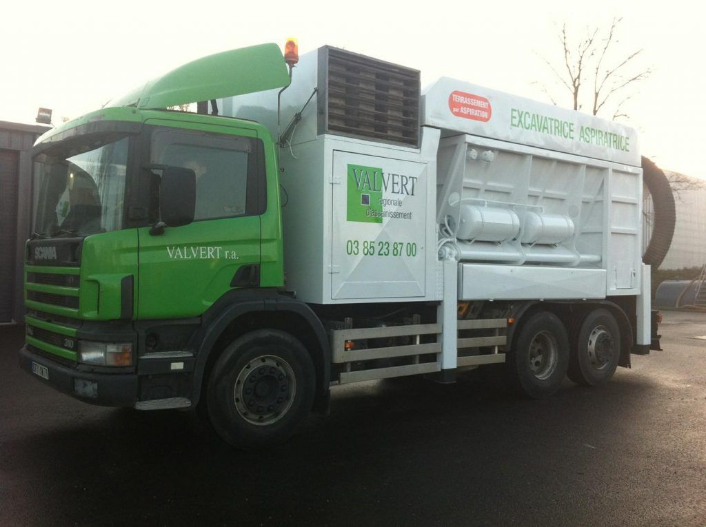Camion de collecte des déchets vert et blanc stationné à l'extérieur, avec l'inscription : « L'EXCELLENCE EN MATIÈRE DE GESTION DES DÉCHETS ».