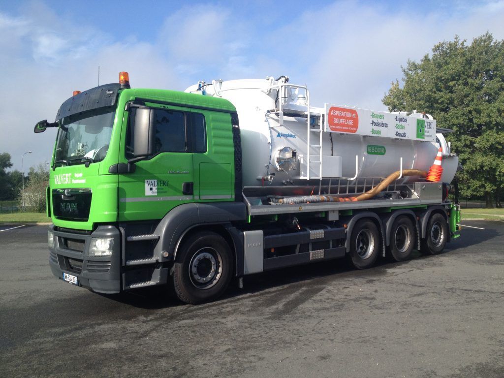 Camion de ramassage des ordures vert et blanc stationné à l'extérieur.