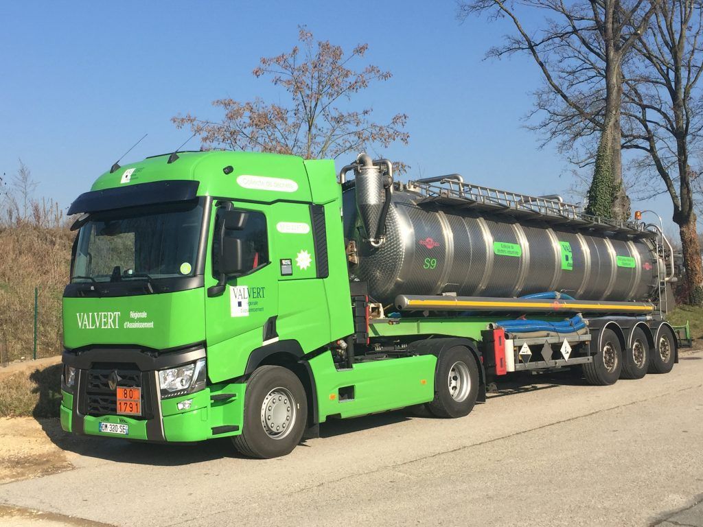 Camion-citerne vert, stationné à l'extérieur par une journée ensoleillée.