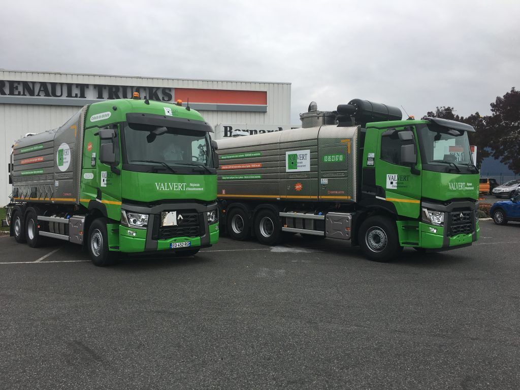 Deux camions-citernes verts et argentés sont stationnés devant une concession Renault Trucks.