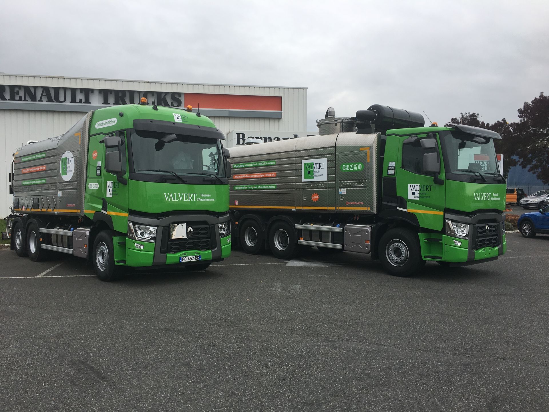Deux camions-citernes verts sont stationnés devant une concession Renault Trucks.