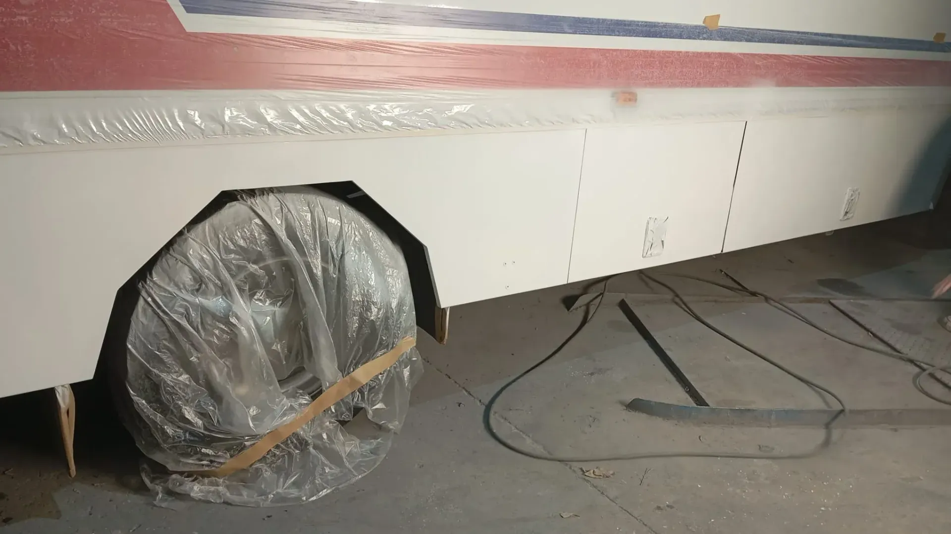 Lateral de autobús pintado de blanco con neumático forrado; configuración de garaje.