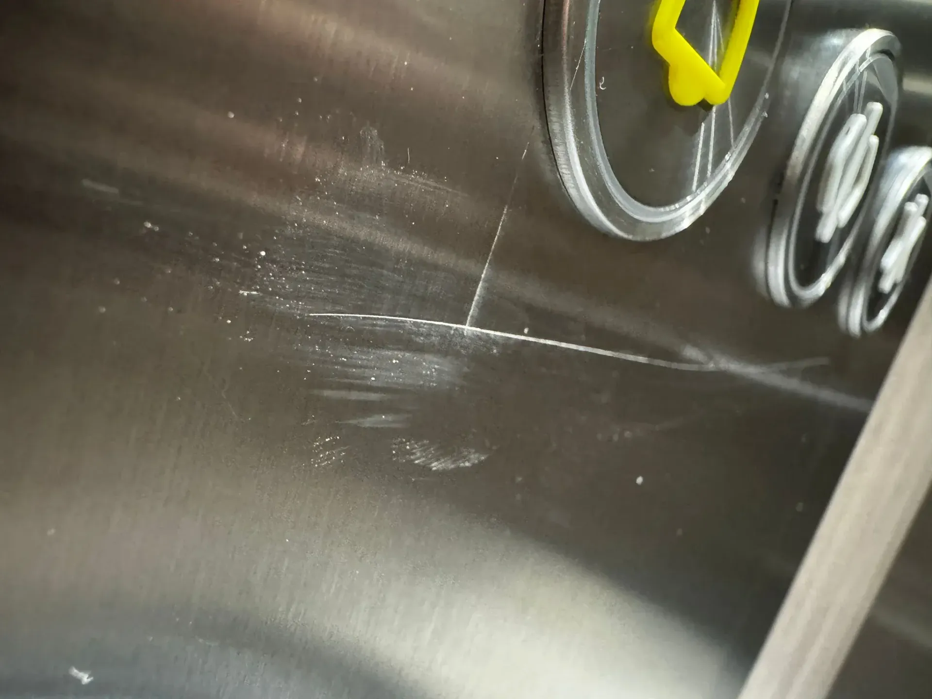 Panel de ascensor de acero inoxidable rayado con botones. Residuos de polvo blanco cerca de los arañazos.