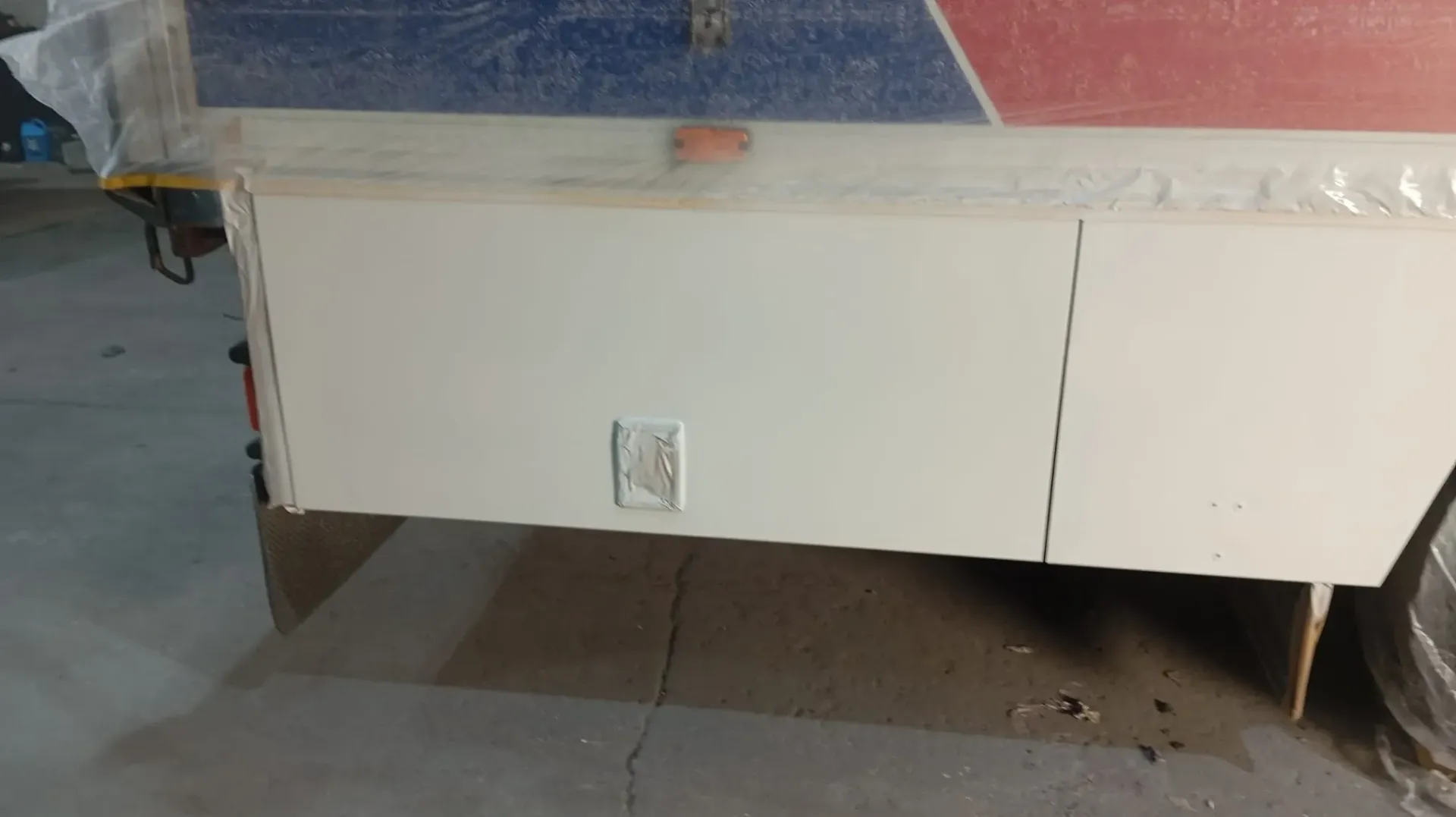 Panel blanco en un camión, con una grieta visible y una toma de corriente eléctrica.