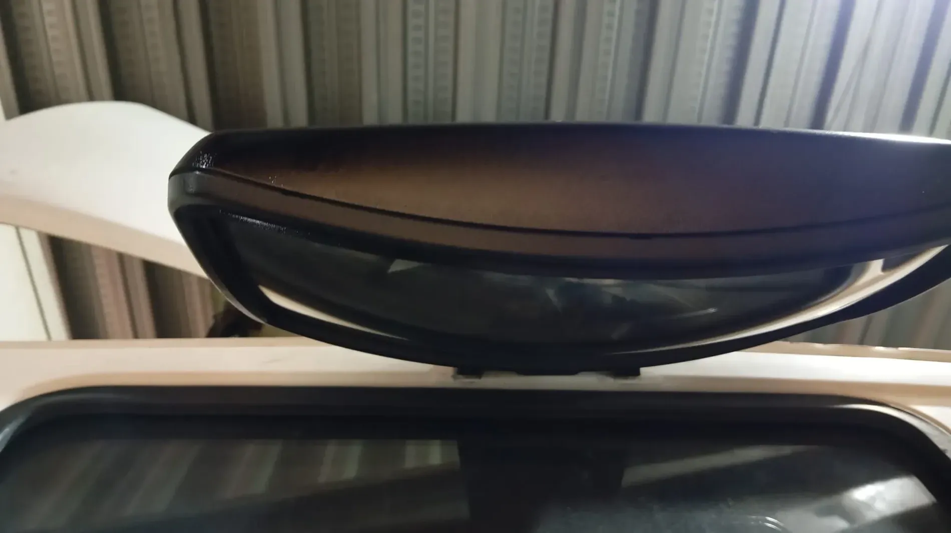 Espejo retrovisor negro en un vehículo blanco con marco de ventana trasera negro.