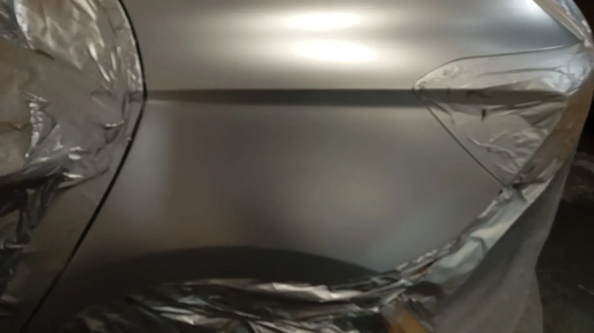 Puerta del coche revestida con lámina de plástico y pintada de color plata.