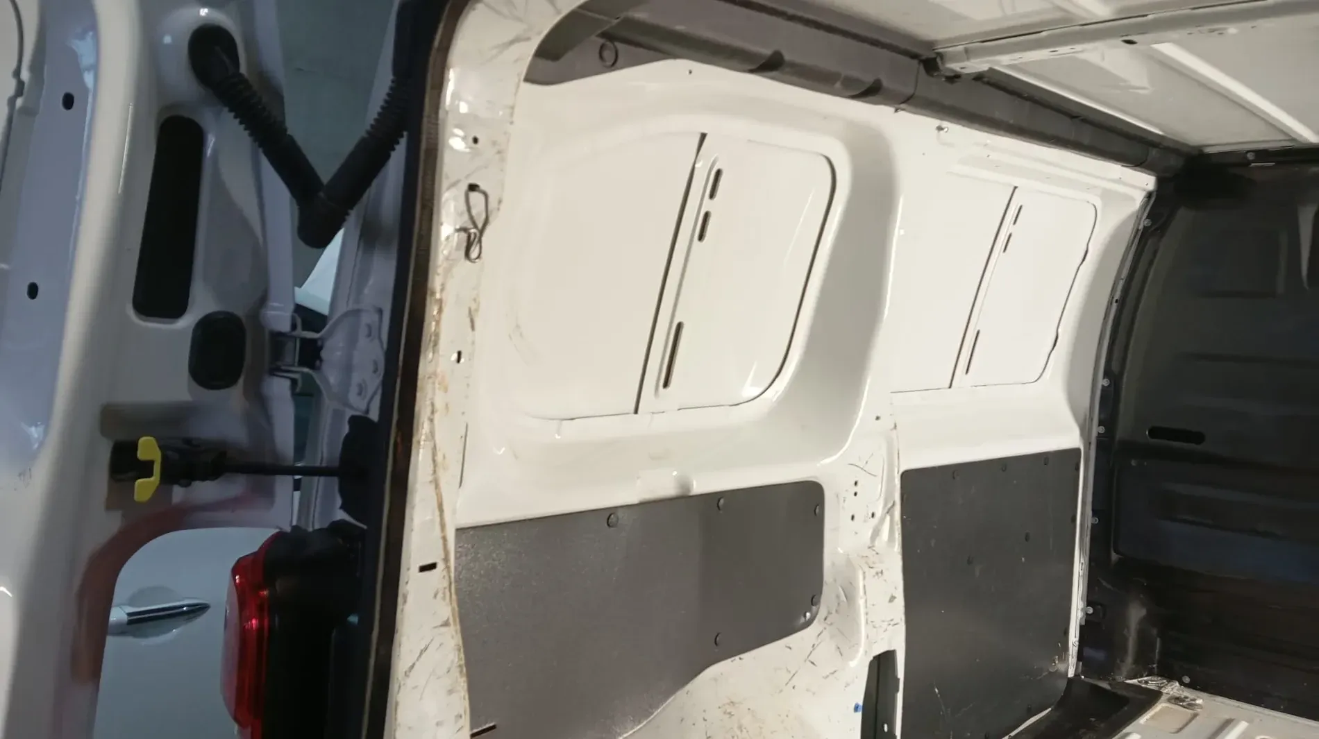 Interior de una furgoneta de carga blanca con paneles en las paredes.