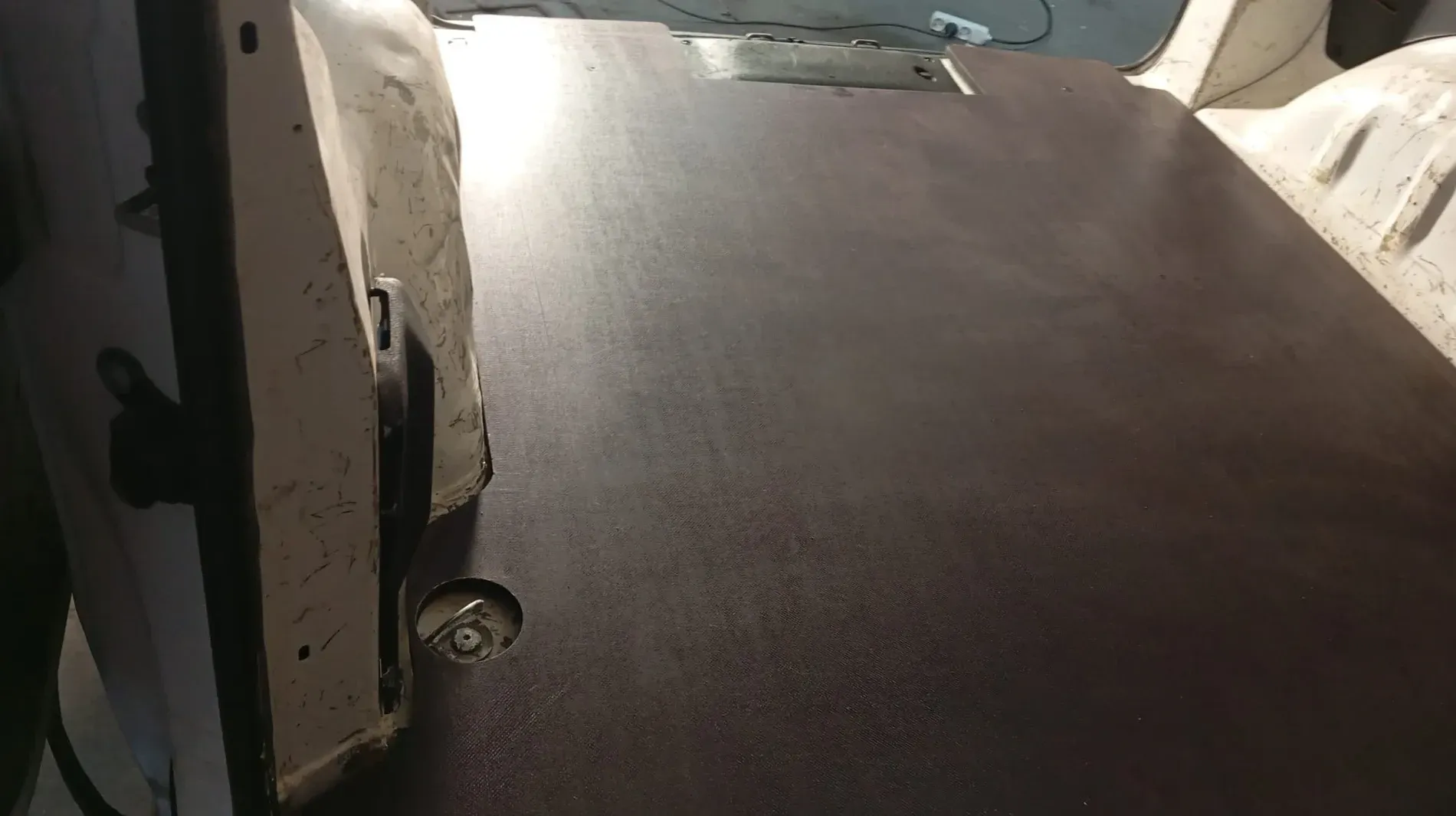 Superficie de madera oscura dentro del interior de un vehículo, posiblemente un piso o paneles.