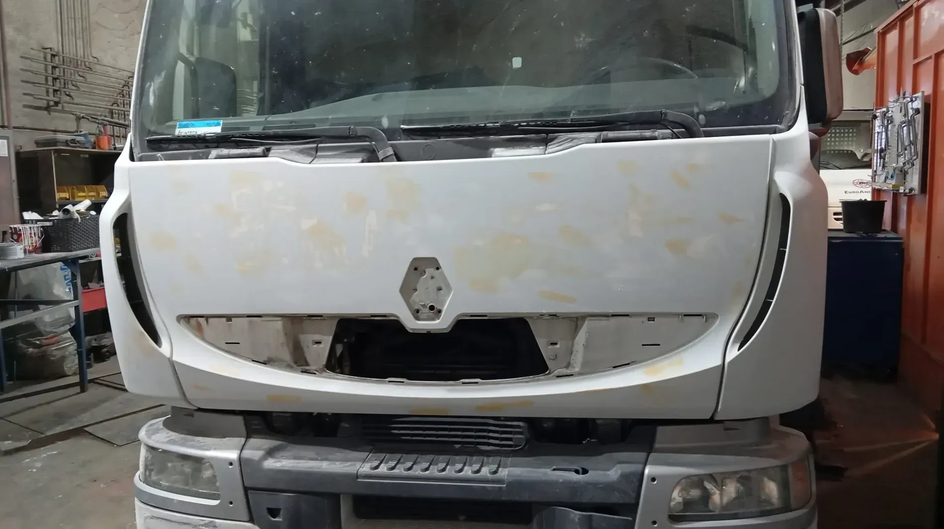 Parte frontal de un camión Renault de color blanco, preparado para pintar, en un taller.