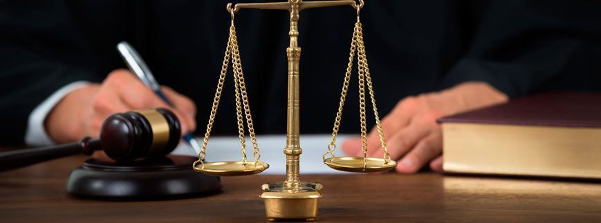 Un juez está sentado en una mesa con un mazo y una balanza de justicia.