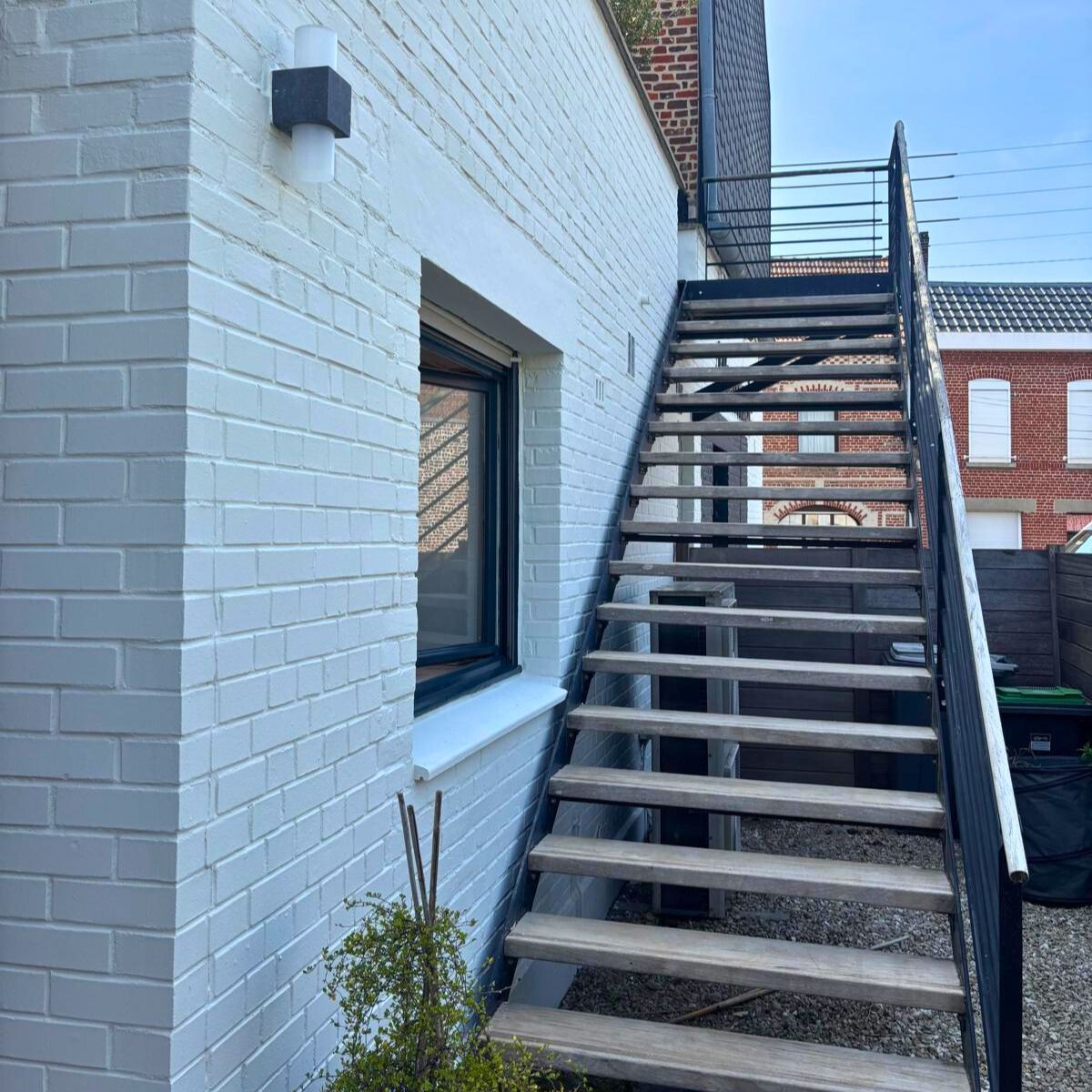 mur en briques peint escalier métallique noir et bois