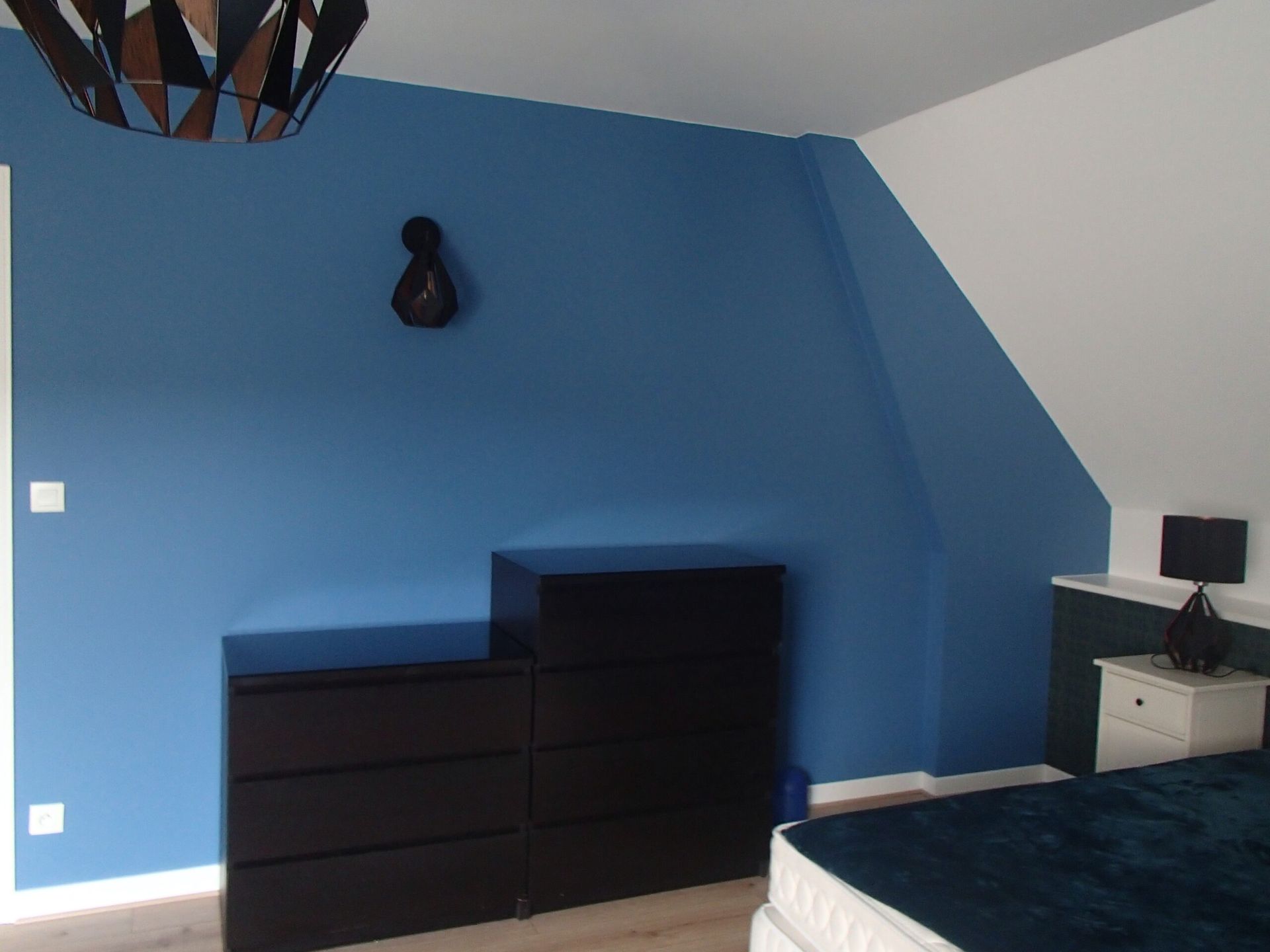 Chambre avec meubles noirs et mur bleu