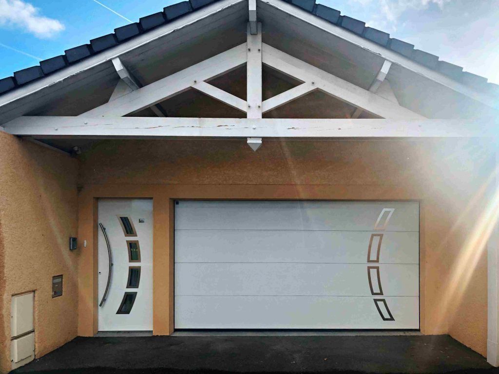 Garage avec porte blanche, porte latérale et toit en pente avec supports en bois.