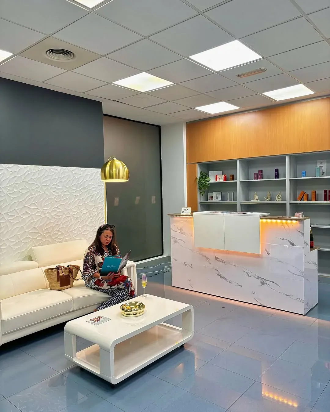 Una mujer está sentada en un sofá leyendo un libro en una sala de espera.