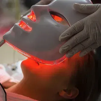 Una mujer está recibiendo un tratamiento de luz roja en su cara.
