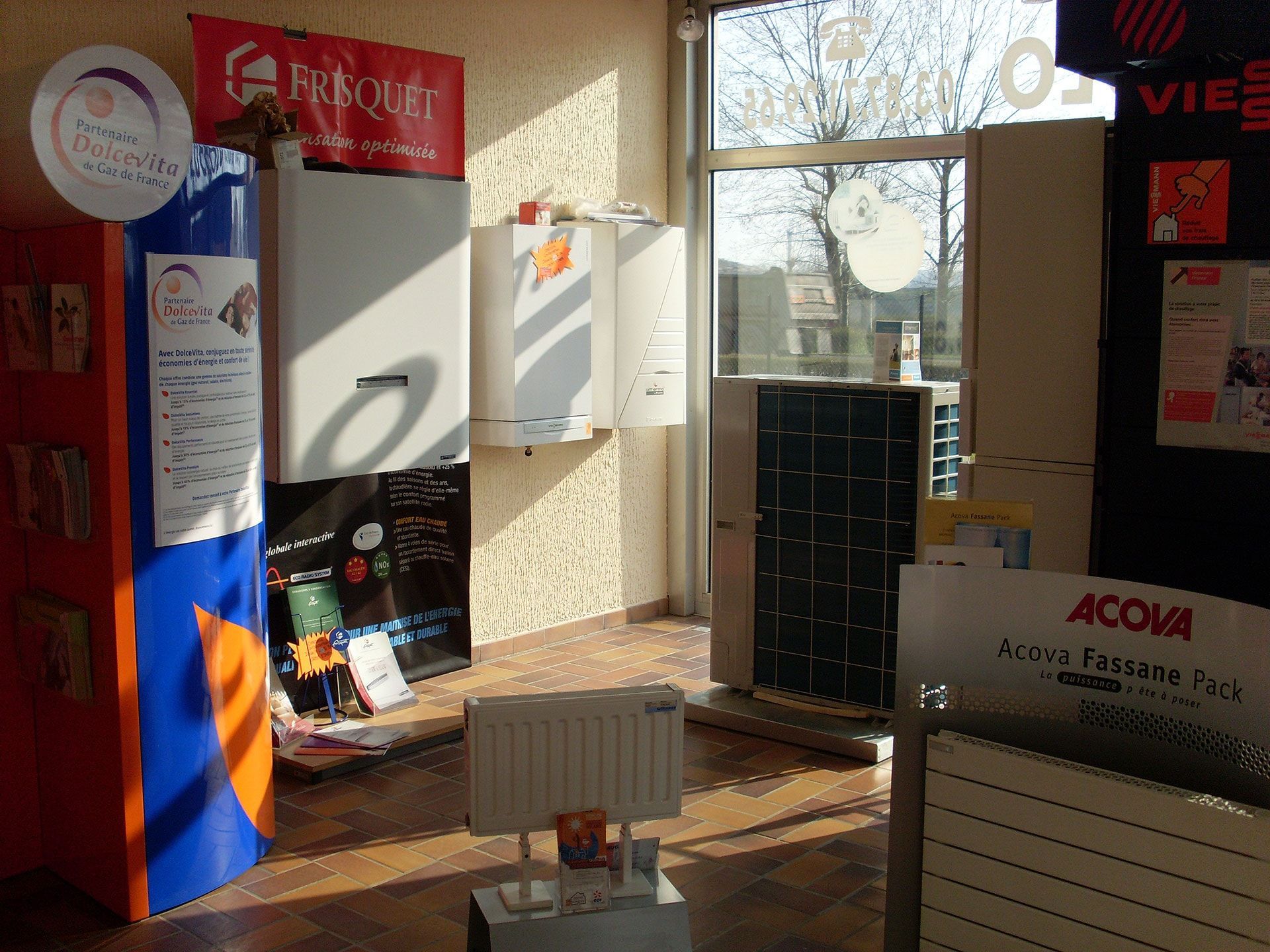 Intérieur d'un magasin présentant du matériel de chauffage : chaudières, radiateurs et un climatiseur.