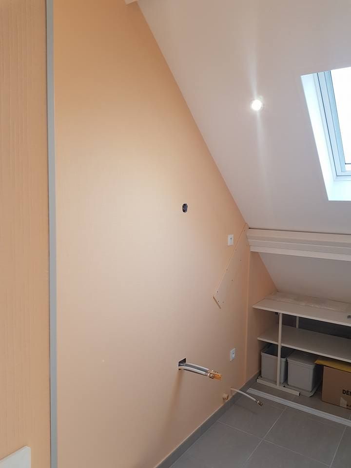 Mur beige en angle avec prises électriques, porte de placard et puits de lumière.