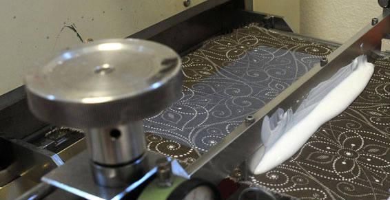 Une machine avec un bouton argenté et un objet blanc aux lignes épurées sur une surface texturée.