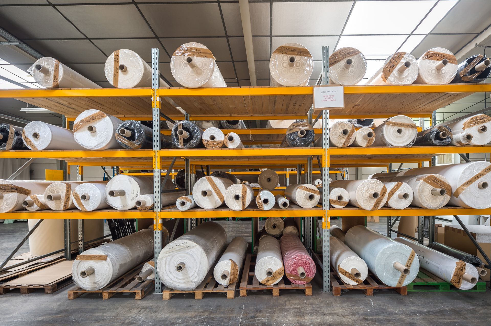 Des étagères remplies de rouleaux de tissu dans un entrepôt.