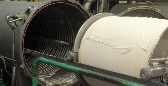 Grande machine industrielle avec rouleau de tissu à l'intérieur, partiellement ouverte pour le chargement.