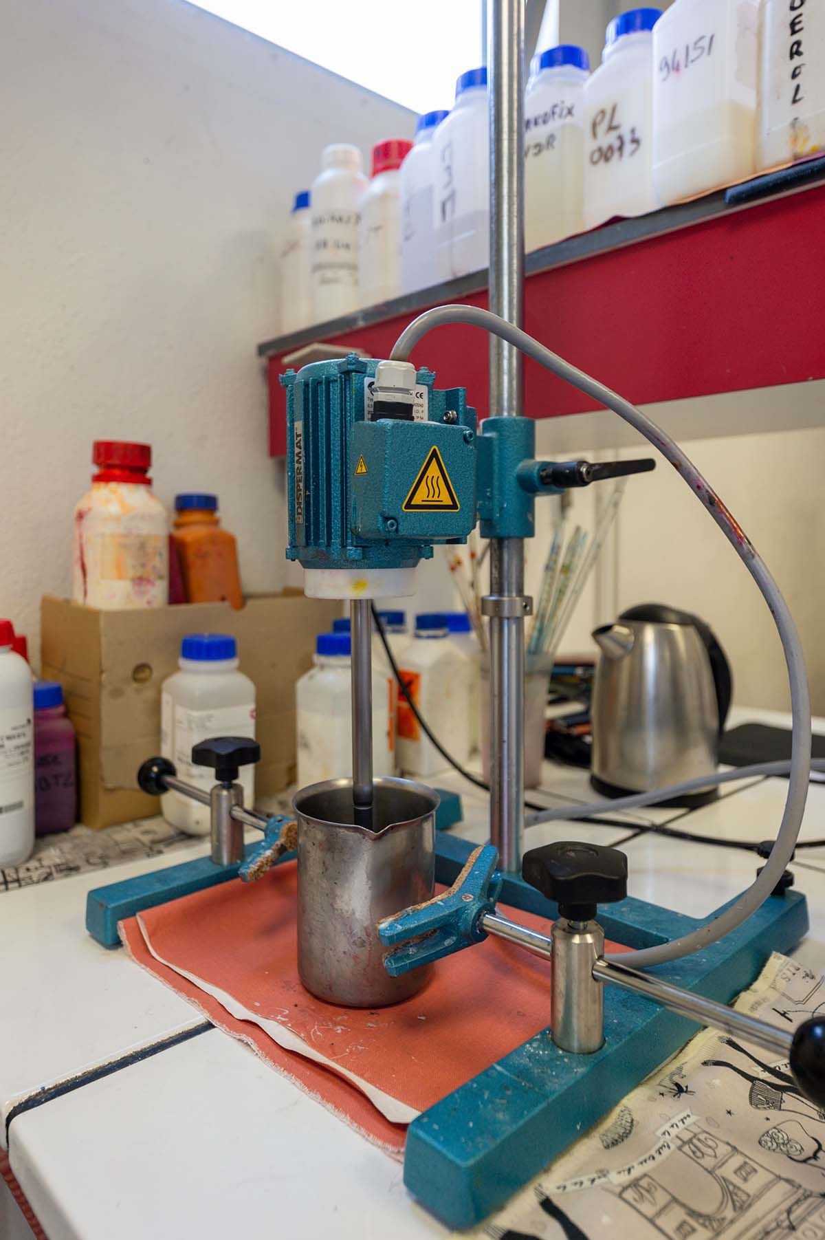 Appareil de mélange de laboratoire comprenant un moteur d'agitation, un bécher en métal et divers flacons de produits chimiques.