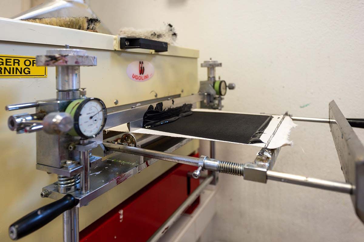 Machine avec un matériau noir en cours de pressage, jauges visibles.