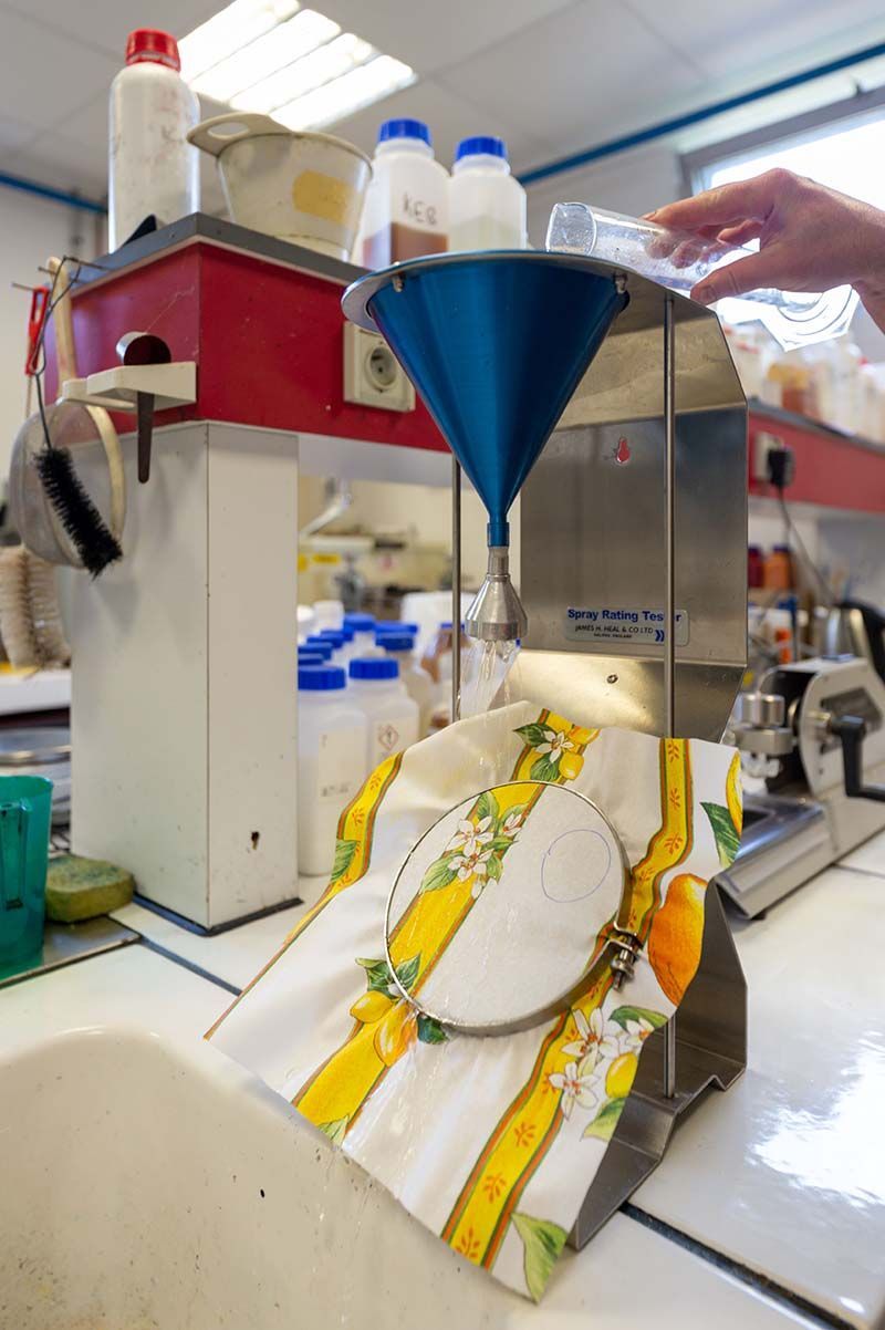 Dispositif de laboratoire comprenant un entonnoir, une balance, des flacons et une personne versant un liquide.