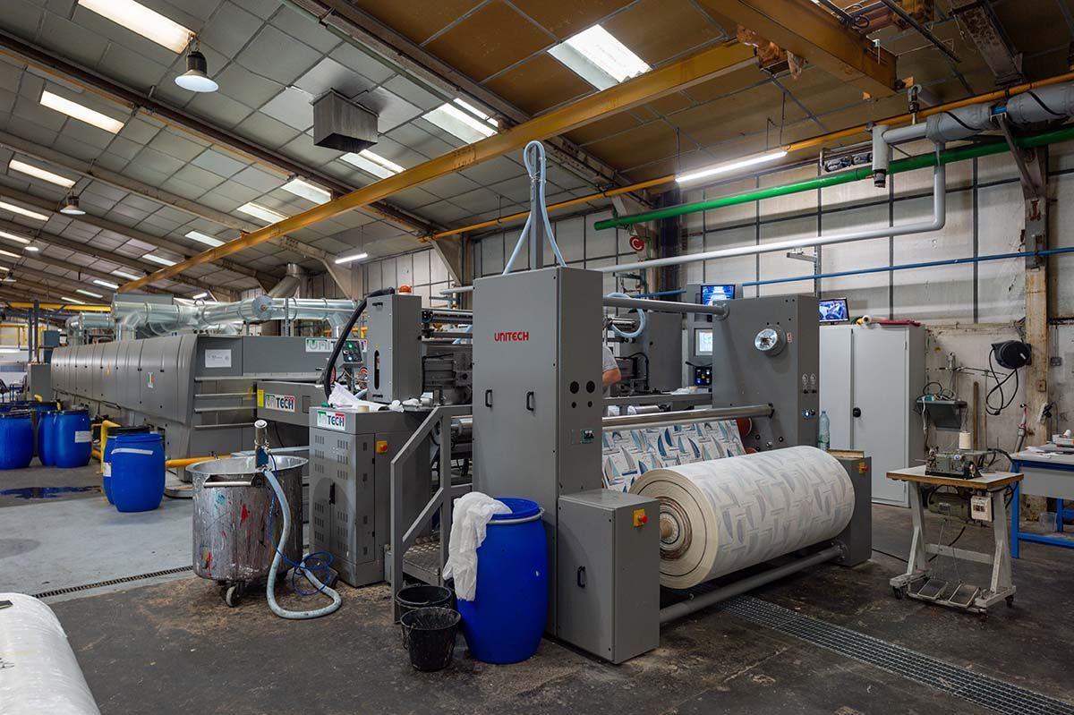 Machines textiles industrielles en usine, traitant des rouleaux de tissu.