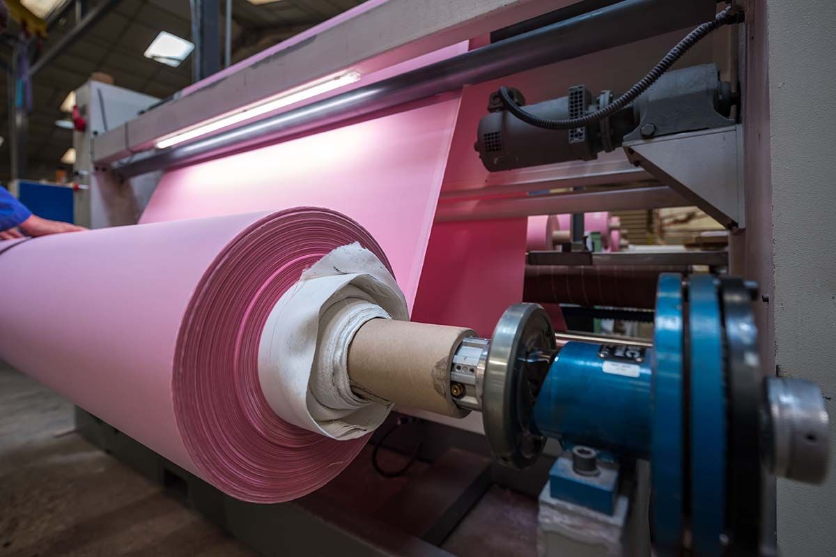 Des rouleaux de tissu rose sur une machine industrielle, probablement pour la production textile.