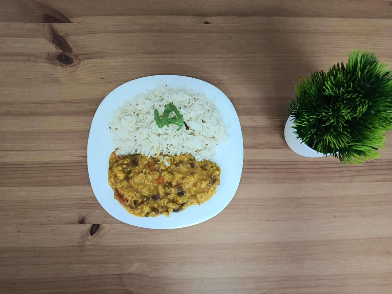Un plato blanco con una porción de arroz con comino, cubierto con una guarnición verde.