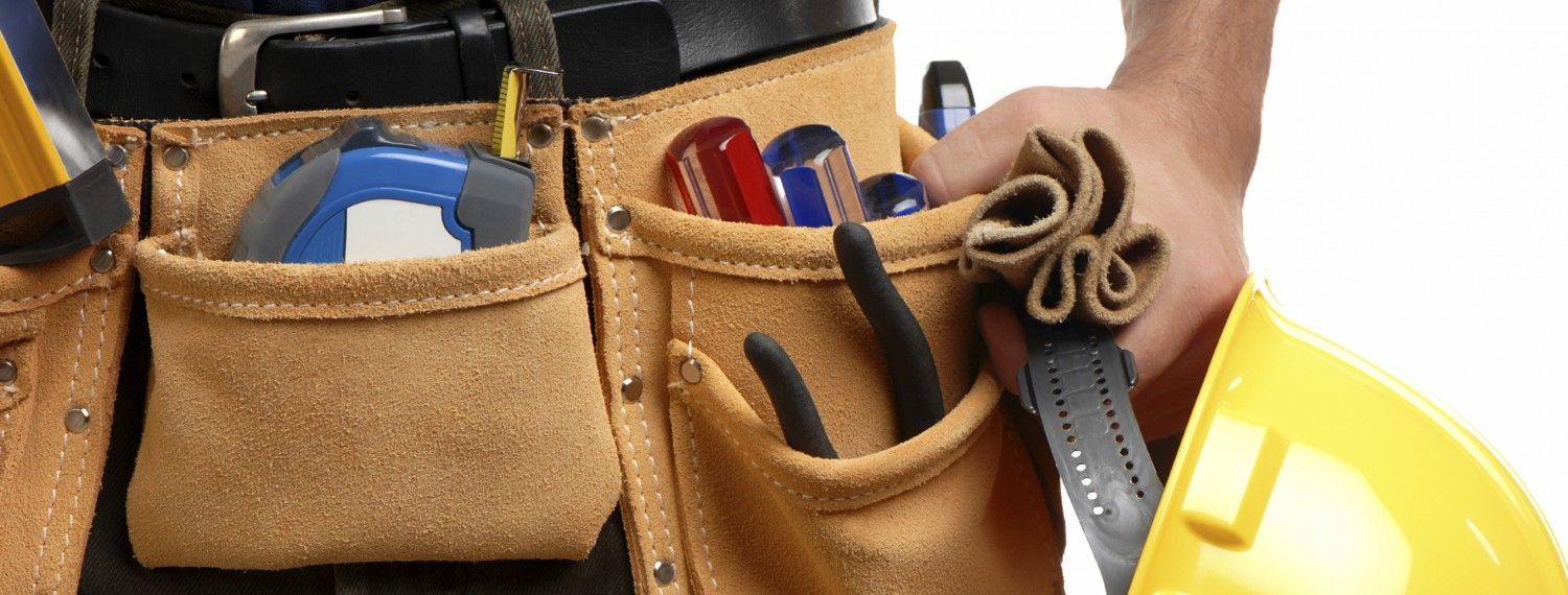 Una persona sostiene un casco y un cinturón de herramientas lleno de herramientas.