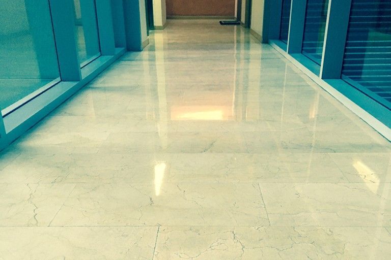 Un pasillo con suelo de mármol y ventanas azules.