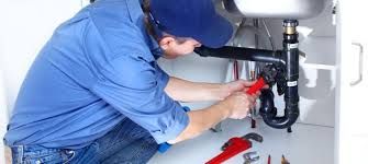 Un fontanero está arreglando un fregadero con una llave inglesa.