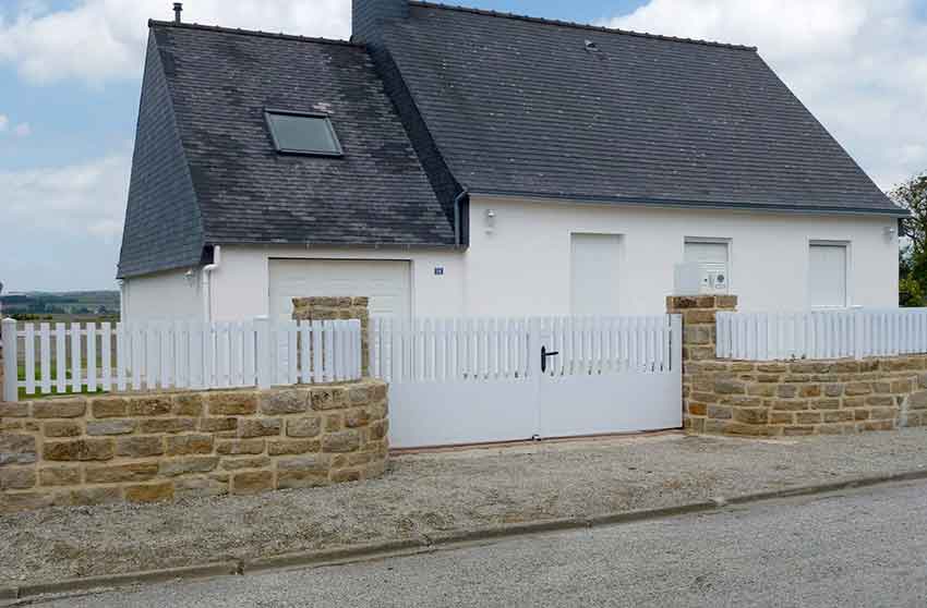 Maison avec un portail blanc et un muret en briques