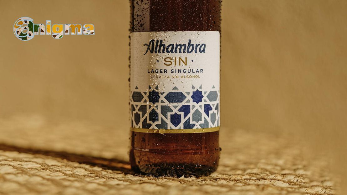 Una botella de cerveza Alhambra está sobre una mesa.