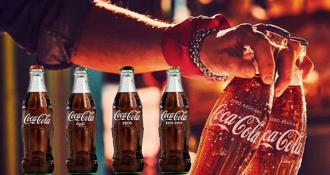 Una persona sostiene una botella de Coca Cola en su mano.