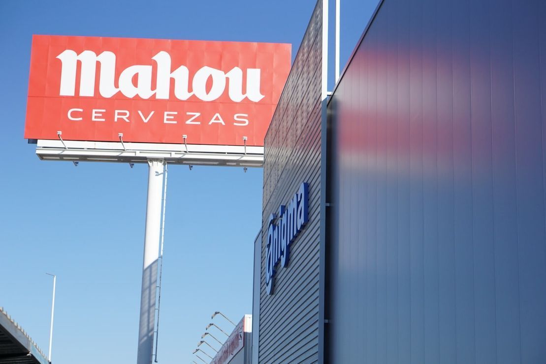 Un cartel de cervezas Mahou está encima de un edificio.