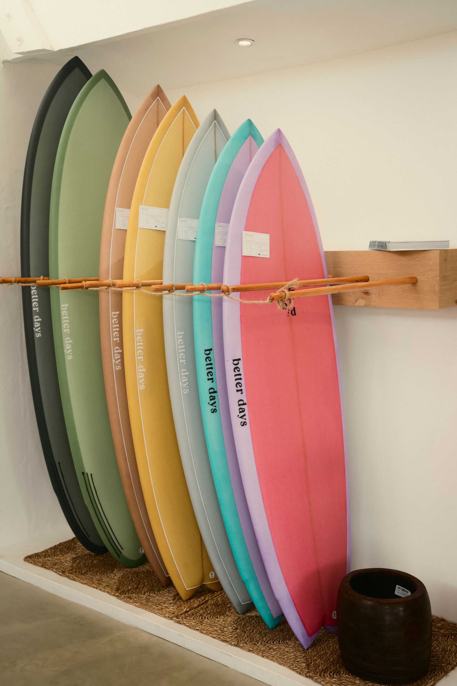Surfboard-Wandhalterung mit sieben Surfbrettern in dunkelgrün, hellgrün, orange, gelb, hellem mint, türkis und dunklem rosa