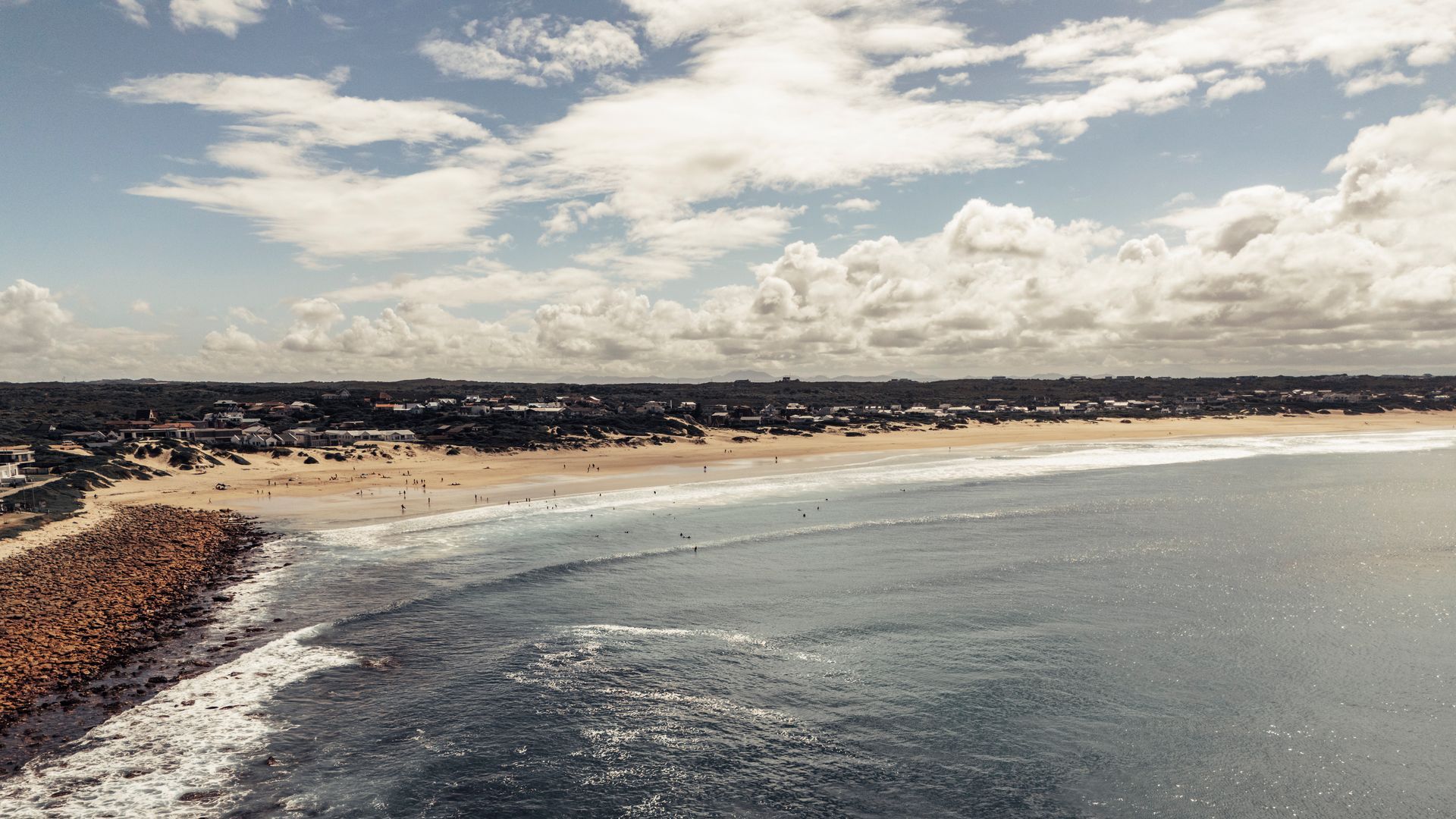 Blick über das Meer an die Küste mit Strand und Wolken am Himmel