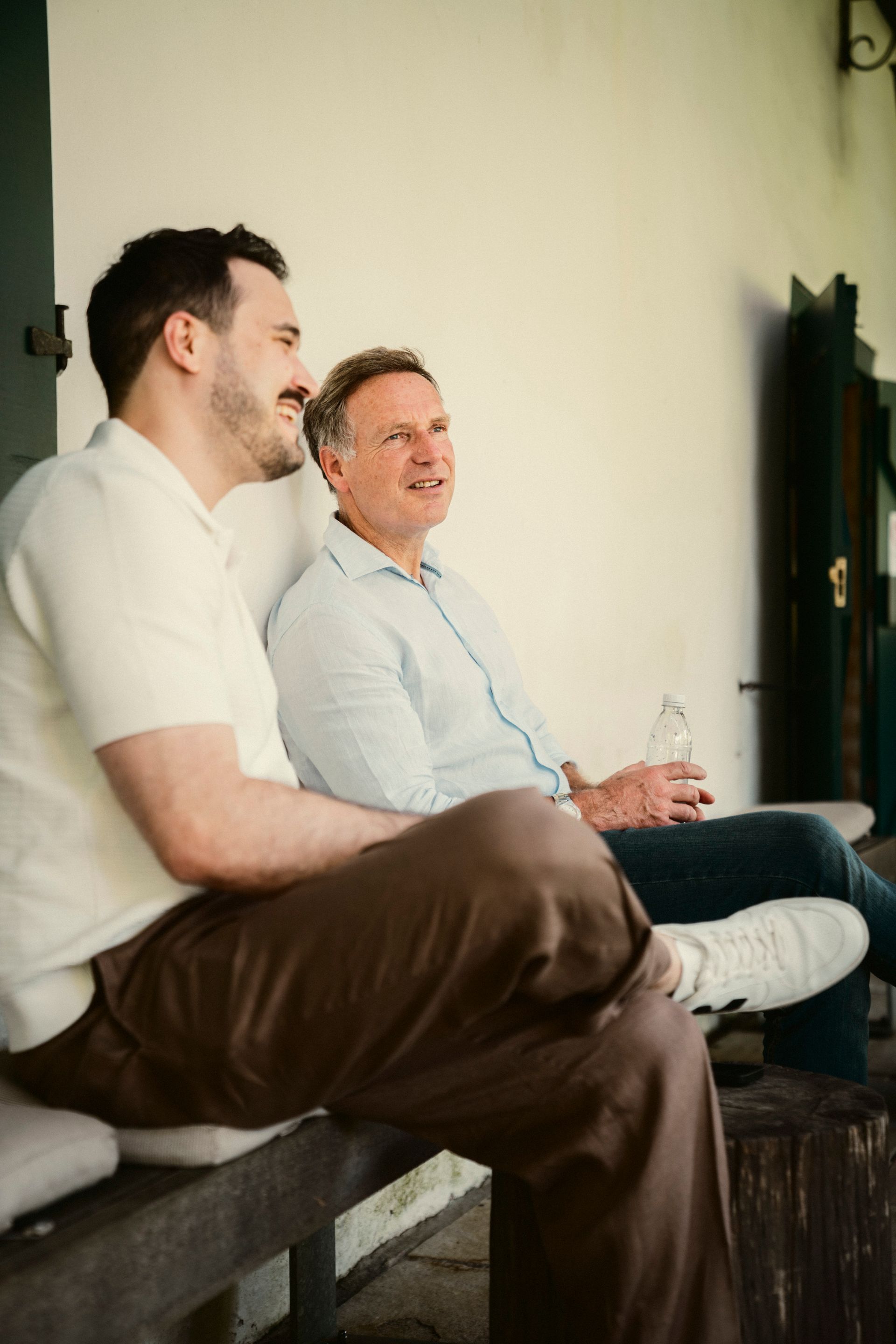 Markus und Lars Maack der Besitzer des Weingutes Buitenverwachting sitzen auf einer Bank und unterhalten sich