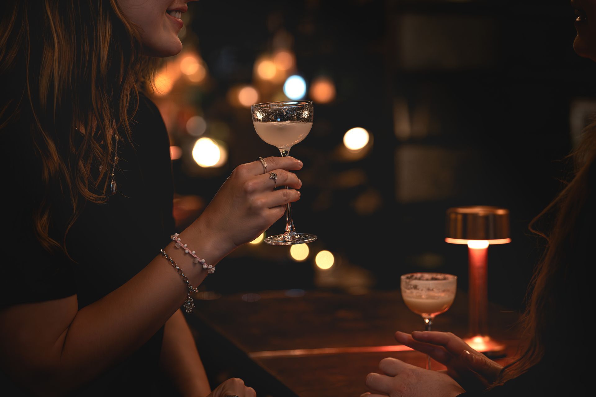 Zwei Frauen sitzen mit Cocktailgläsern in der Hand in der Three Fingers Bar.