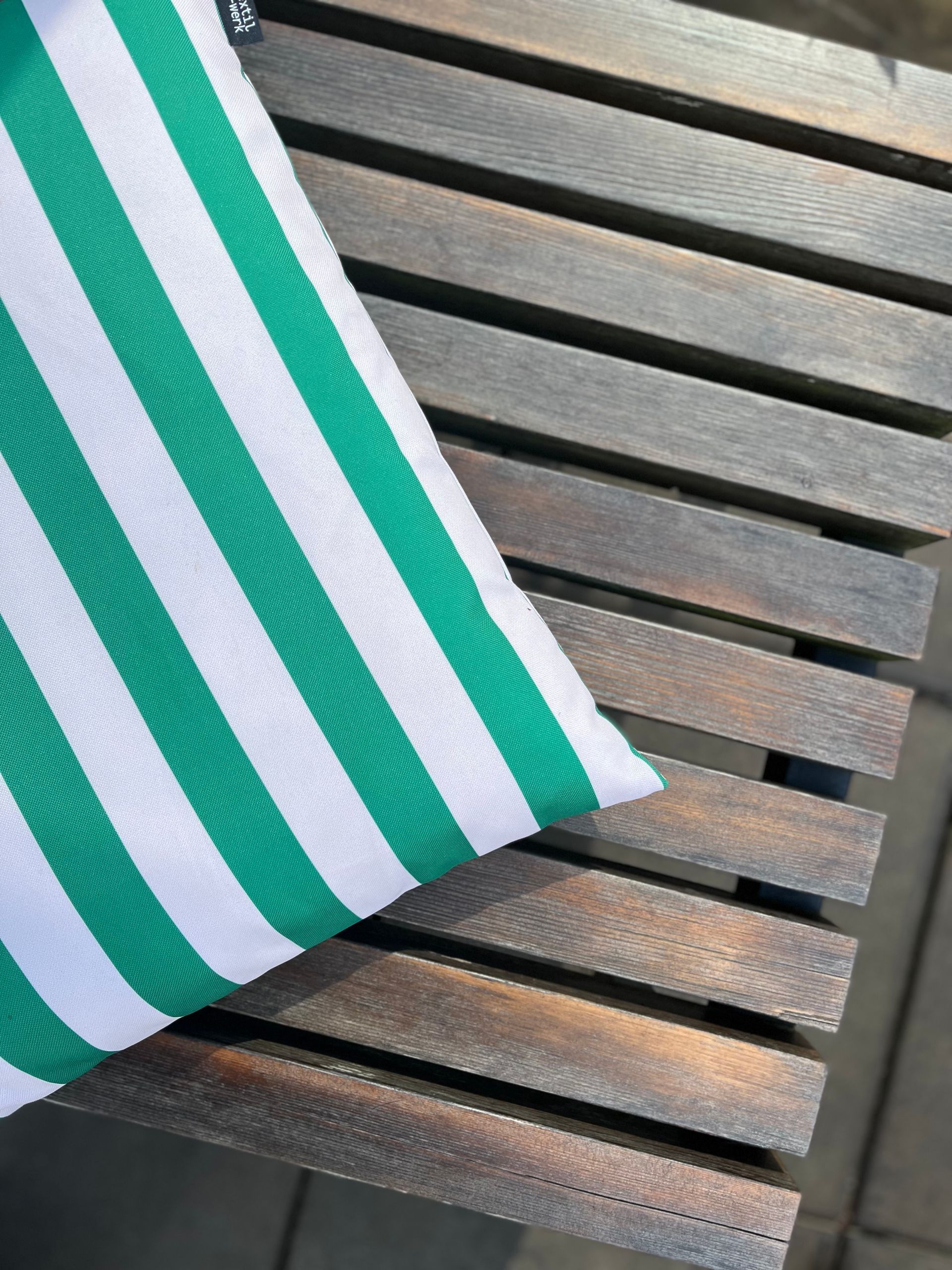 Gestreiftes Kissen auf Holzbank