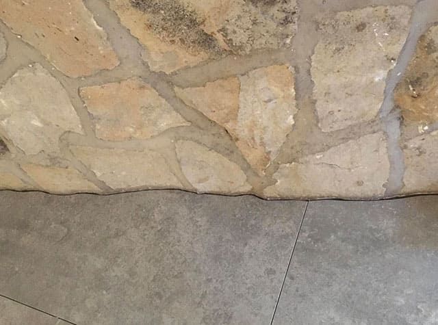 Eine Nahaufnahme einer Steinmauer und eines Fliesenbodens.