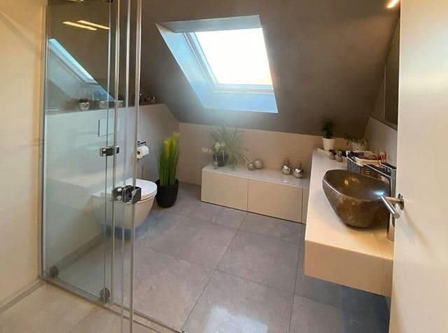 Ein Badezimmer mit Toilette, Waschbecken, Dusche und Oberlicht.