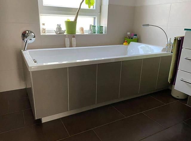 In einem Badezimmer steht eine Badewanne neben einem Fenster.