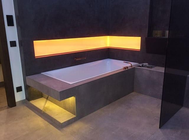 Eine Badewanne in einem Badezimmer mit einem gelben Licht dahinter