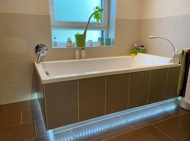 In einem Badezimmer steht eine Badewanne neben einem Fenster.